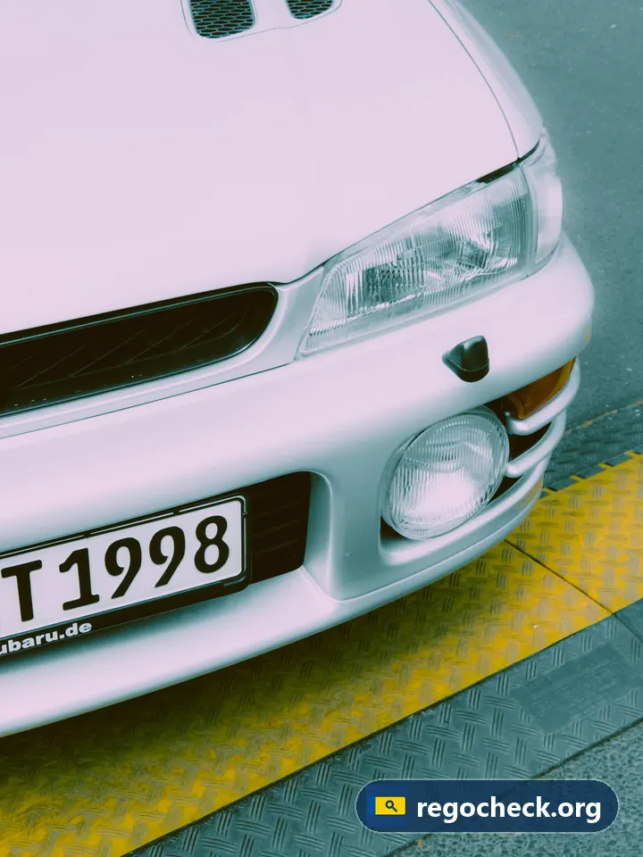 Bijzondere kentekens: witte Subaru Impreza van voren met kentekenplaat, jaartal 1998 zichtbaar